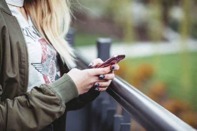 Lady on bridge looking at iphone | Kelly Chandler Consulting