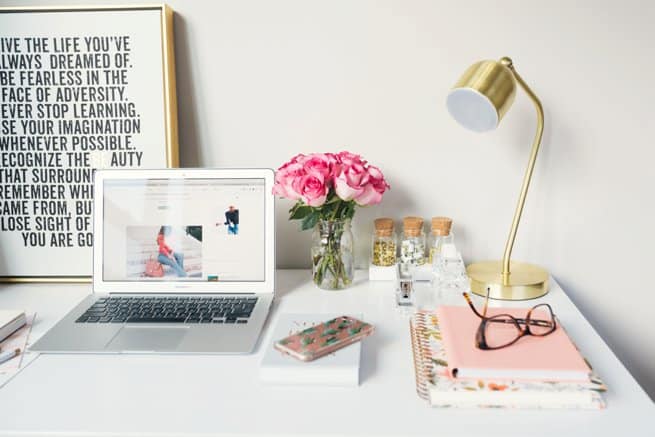 Styled desk with laptop roses in a vase and stacked books with glasses on top | Kelly Chandler Consulting
