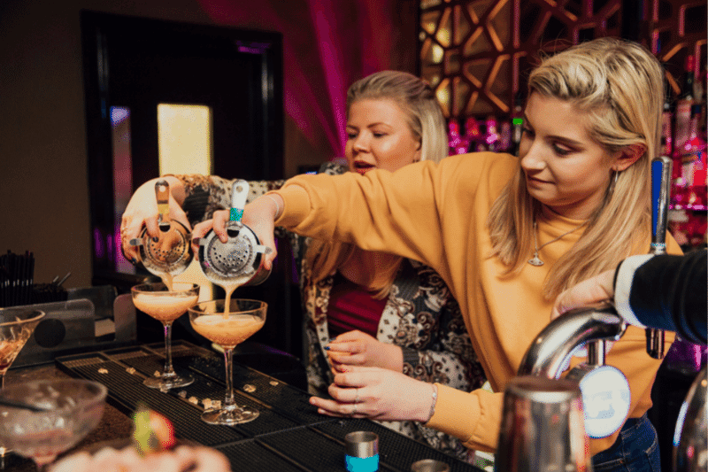 Two woman having a cocktail making lesson extra wedding revenue