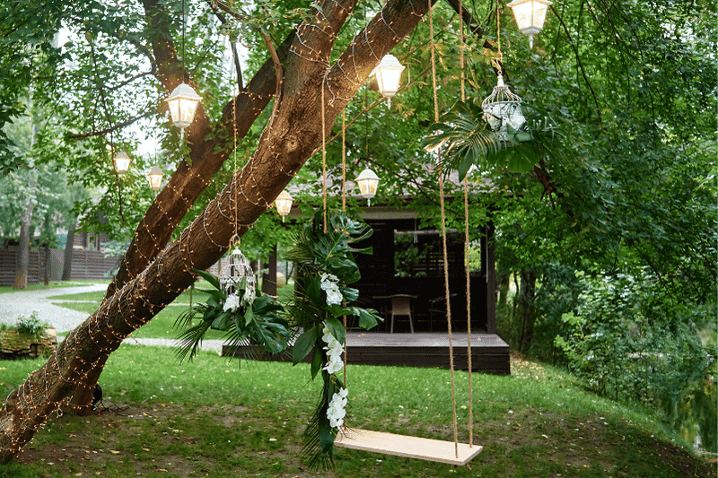 Outdoor tree swing with fairy lights and lanterns wedding venue props