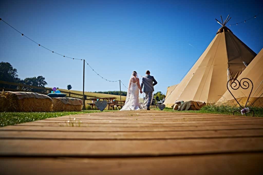Bridal couple walking by a teepee