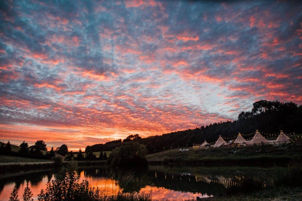 Sunset over a late with teepees on the bank