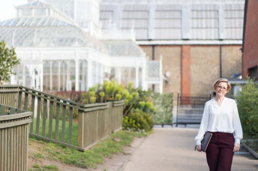 Lady standing outside a wedding venue holding a laptop